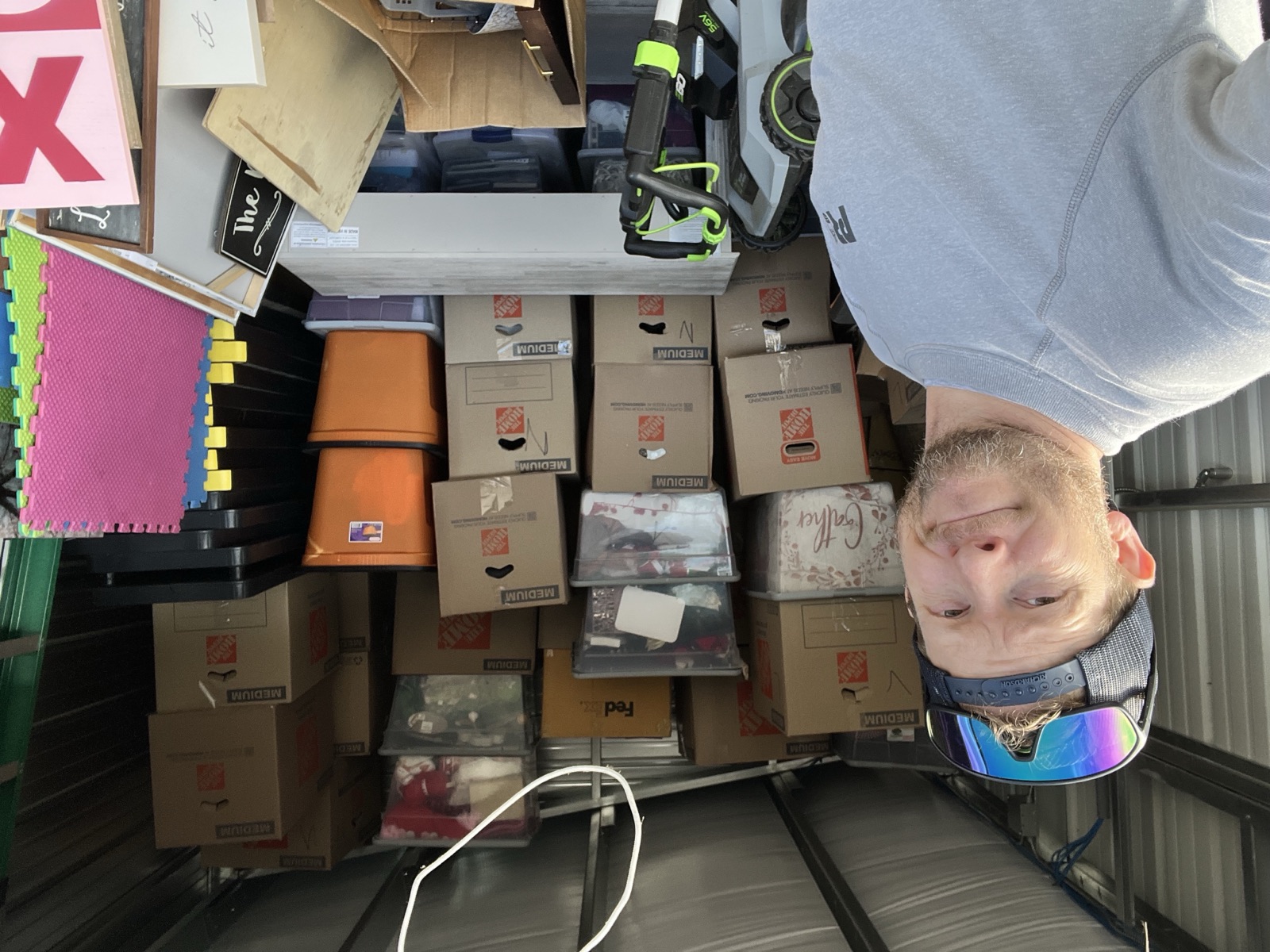 Josh in a storage unit surrounded by cardboard boxes — the "so much stuff" moment every move eventually hits